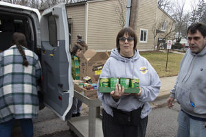 A female resident of St. Louis Center carrying a case of canned goods.