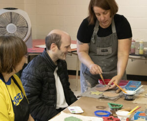 Clay artist teaching a disabled person about clay