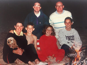 Mom, Dad, their four children and the family dog at a campfire