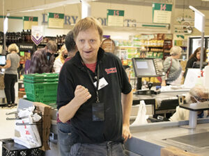 A man with developmental disabilities is working as a bagger in a supermarket.