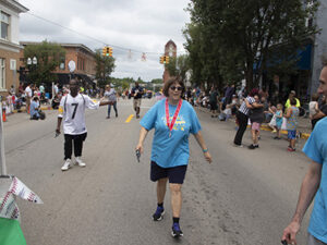 A woman with developmental disabilities is walking in a parade through downtown Chelsea MI