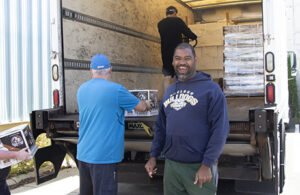 Several men loading a box truck with cases of beverages.