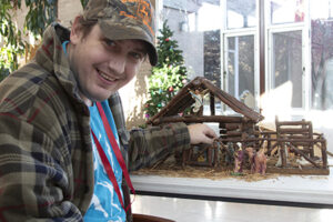 A man with developmental disabilities is setting up a nativity scene.