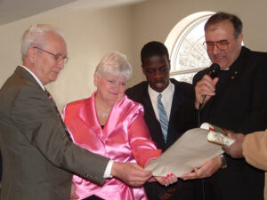 A mature couple looking at a document with a black teen and an Italian priest.