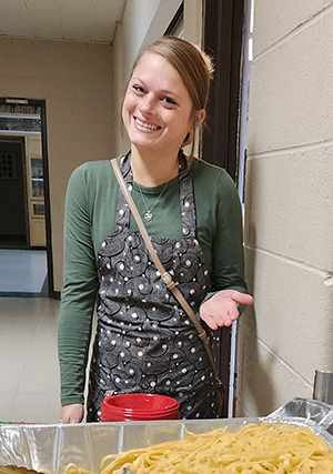 A smiling young white female wearing an apron.