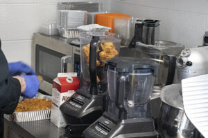 Two commercial grade food blenders on the counter in a kitchen.