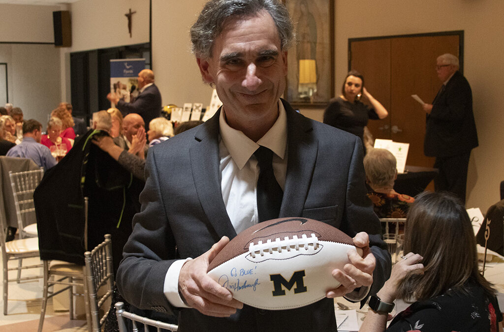 A mature man with intellectual disabilities holding a University of Michigan football.