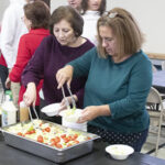 Mature Italian women serving salads in the St. Louis Center gym.