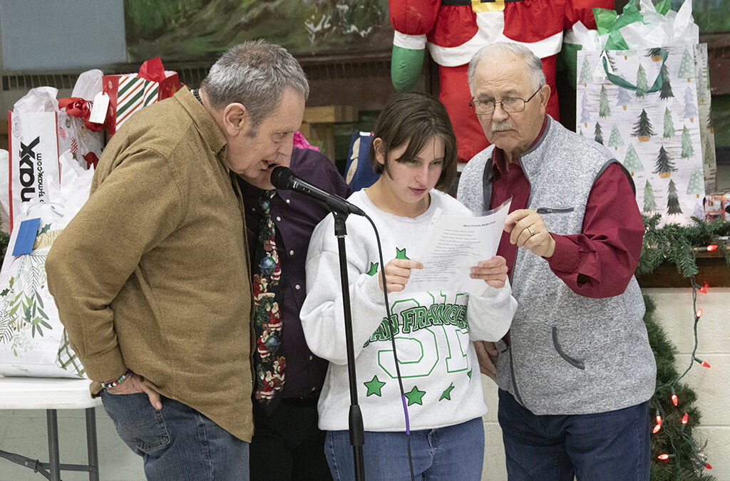 a mature Italian man is at a microphone with two adults with disabilities.