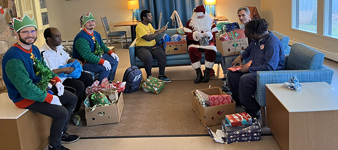 Santa and two elves are in the living room of St. Joseph Hall delivering gifts to St. Louis Center residents.