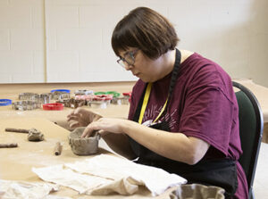 A woman is making a bowl out of clay.