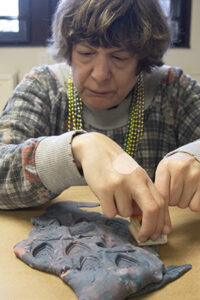 An adult woman with disabilities working with clay.