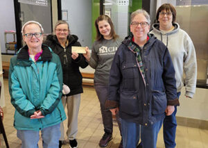 Four women with disabilities presenting a check to a woman at an animal shelter.