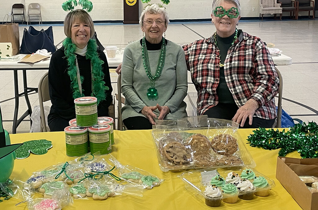 Three mature women wearing casual clothes ad St. Patrick's Day accessories