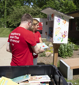 A man and woman filling a tiny library with books